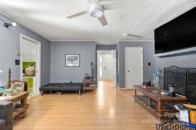 1210 Brookwood Dr, Shelby, NC 28150 - living room with light wood-style flooring, a ceiling fan, a textured ceiling, a fireplace, and ornamental molding
