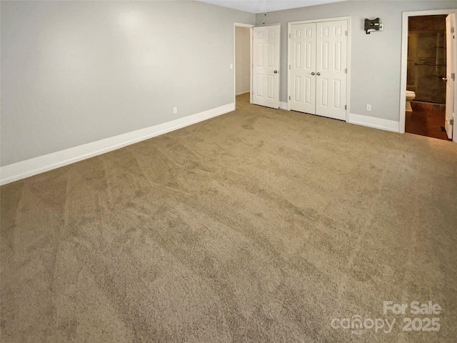 unfurnished bedroom featuring a closet, carpet flooring, baseboards, and ensuite bathroom