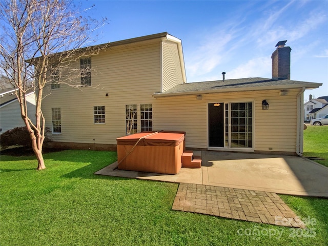 back of house with a yard, a chimney, a patio, and a hot tub