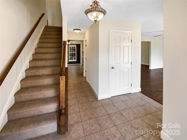 stairs with tile patterned flooring, a ceiling fan, and baseboards