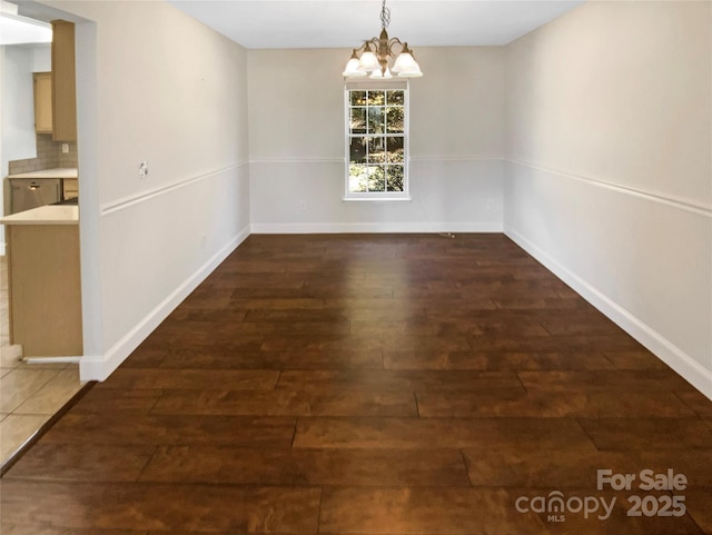 unfurnished dining area with a notable chandelier, baseboards, and wood finished floors