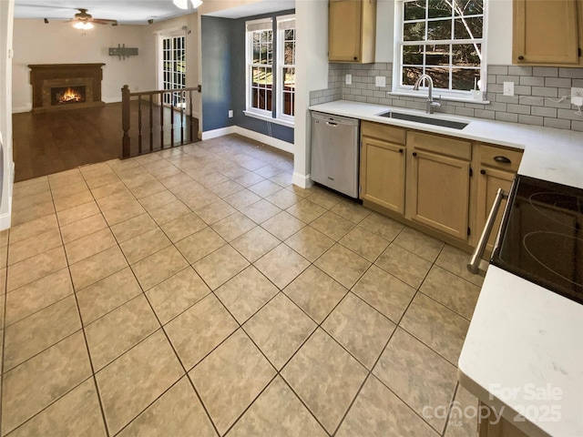 kitchen featuring dishwasher, light countertops, backsplash, and a sink