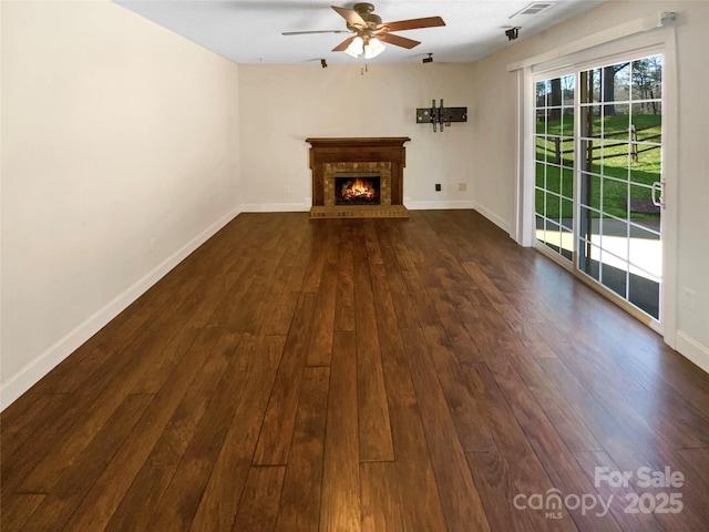 unfurnished living room featuring dark wood-type flooring, a fireplace, and baseboards