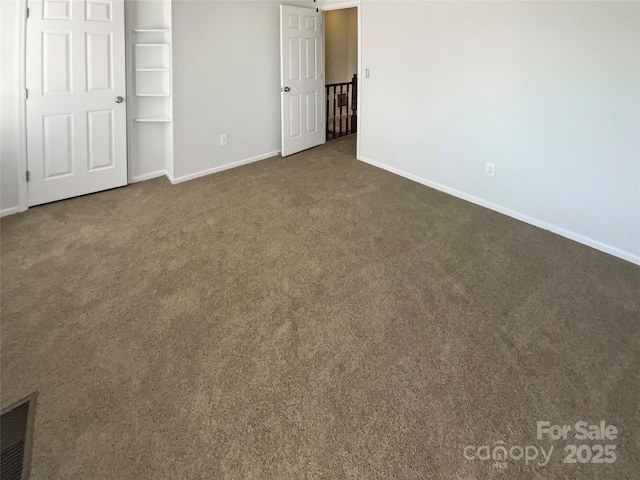 unfurnished bedroom featuring dark carpet, visible vents, and baseboards