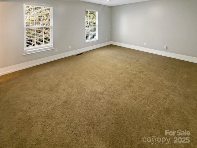 unfurnished room with dark carpet, visible vents, and baseboards