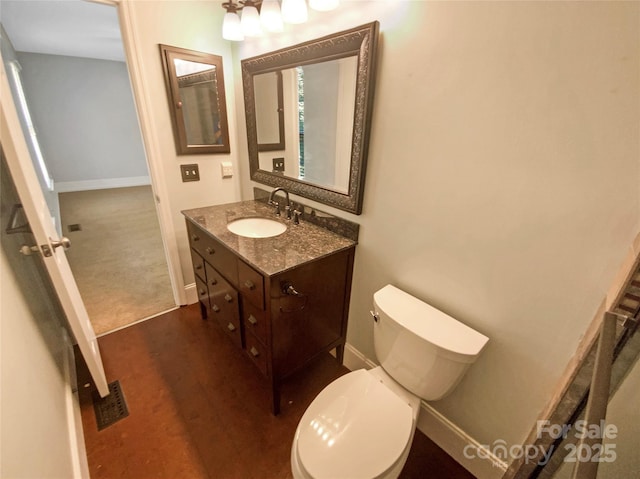 half bath featuring toilet, baseboards, visible vents, and vanity