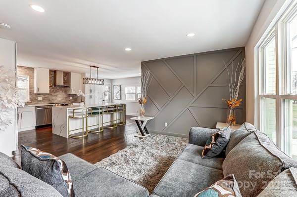 living area with recessed lighting, dark wood-style flooring, and a decorative wall