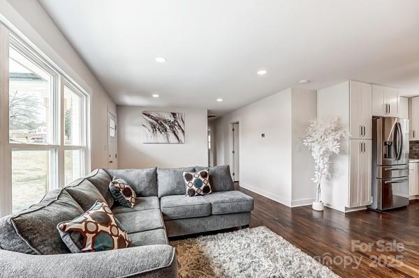 living room featuring dark wood-style floors, recessed lighting, and baseboards