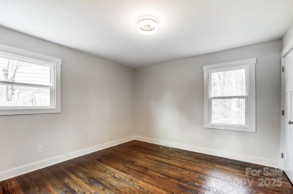 spare room featuring dark wood-style flooring and baseboards