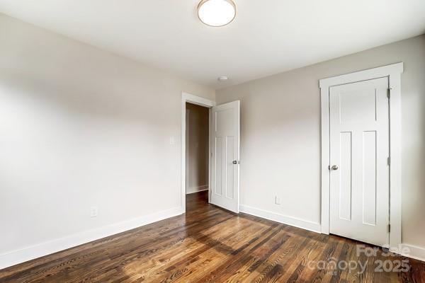 unfurnished bedroom with dark wood-type flooring and baseboards