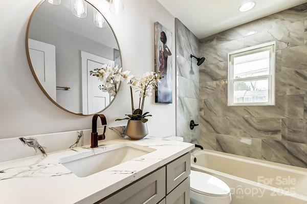 bathroom with toilet, vanity, and shower / bathing tub combination