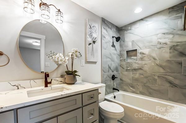 bathroom featuring vanity, toilet, and shower / bathtub combination