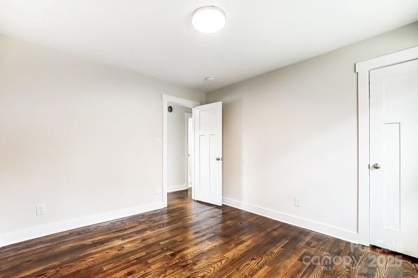 empty room with baseboards and dark wood-style flooring