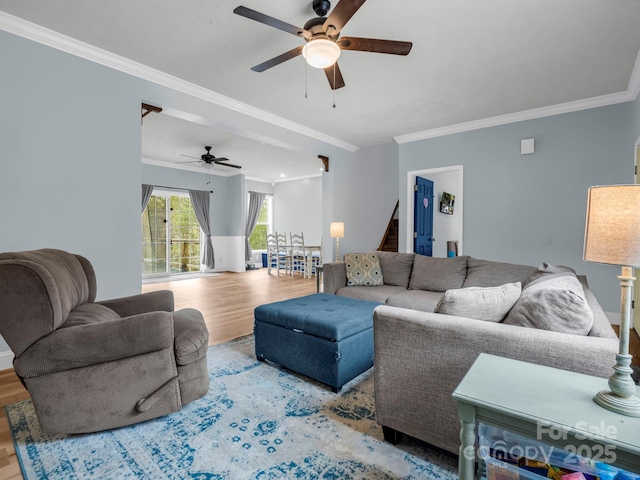 living area with stairs, ceiling fan, wood finished floors, and ornamental molding