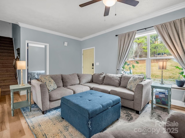 living area with stairway, crown molding, ceiling fan, and wood finished floors