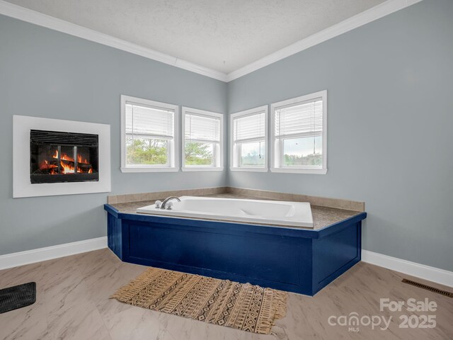 full bathroom with baseboards, a textured ceiling, a glass covered fireplace, crown molding, and a bath