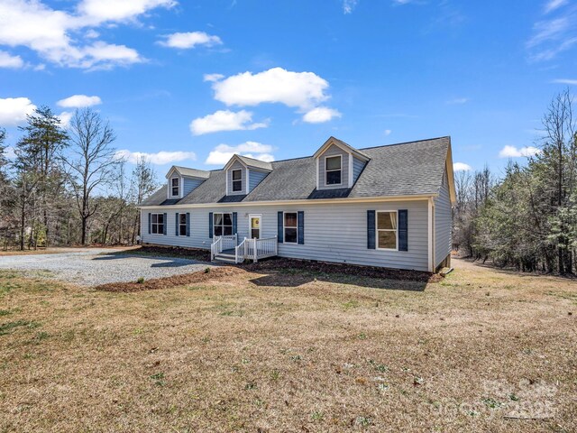 new england style home featuring a shingled roof and a front lawn