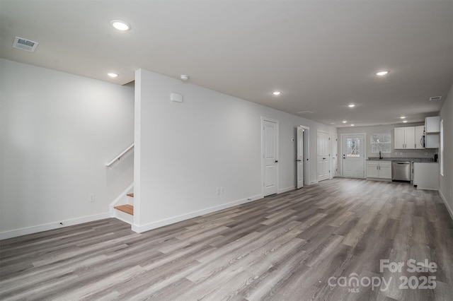 unfurnished living room featuring baseboards, visible vents, wood finished floors, stairs, and recessed lighting