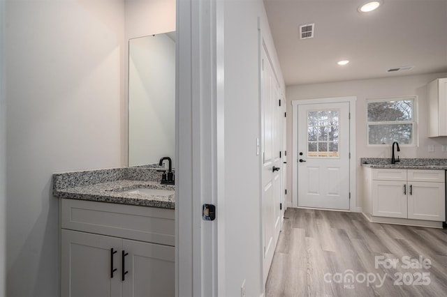 bathroom featuring a sink, wood finished floors, two vanities, and recessed lighting