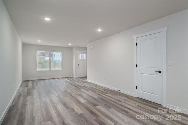 spare room with baseboards, wood finished floors, and recessed lighting