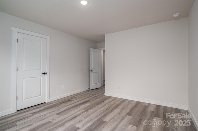 unfurnished room with light wood-type flooring and baseboards