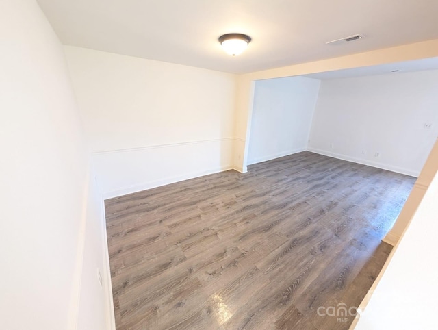 unfurnished room with wood finished floors, visible vents, and baseboards