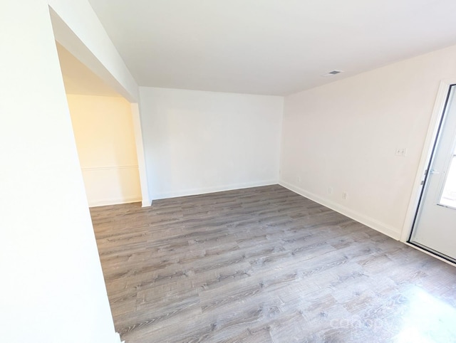 unfurnished room with wood finished floors, visible vents, and baseboards