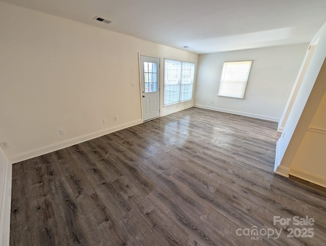 unfurnished room featuring visible vents, dark wood finished floors, and baseboards