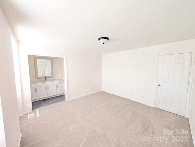 unfurnished bedroom with light carpet, visible vents, and ensuite bathroom