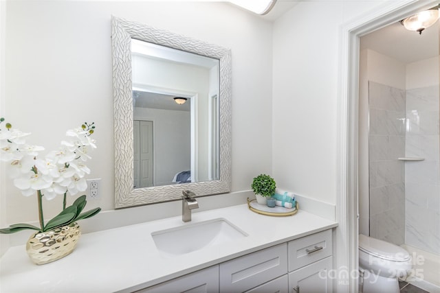 bathroom featuring toilet, tiled shower, and vanity