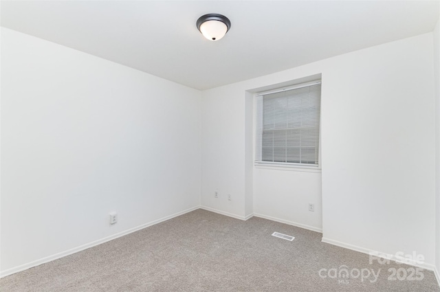 carpeted empty room featuring baseboards and visible vents