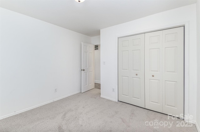 unfurnished bedroom featuring carpet floors, visible vents, baseboards, and a closet