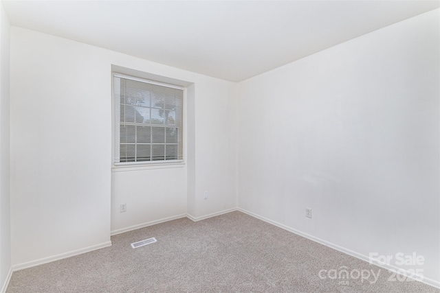 unfurnished room with baseboards, visible vents, and carpet flooring