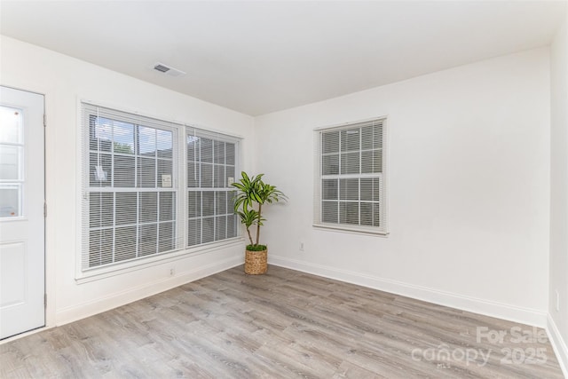 spare room with visible vents, baseboards, and wood finished floors