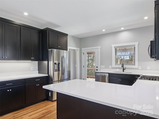 kitchen with recessed lighting, light countertops, appliances with stainless steel finishes, light wood-style floors, and a sink