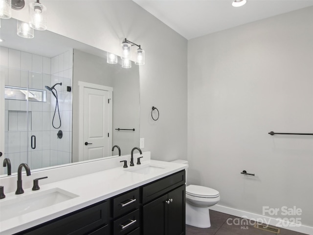 full bathroom featuring toilet, a sink, visible vents, and a shower stall