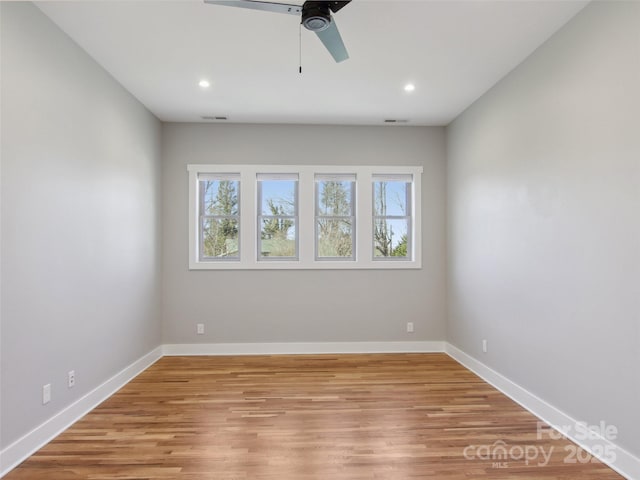 empty room with a wealth of natural light, light wood finished floors, and baseboards