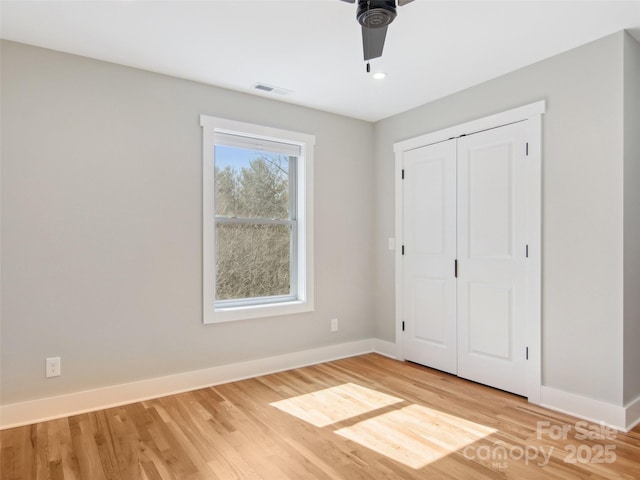 unfurnished bedroom with light wood finished floors, visible vents, baseboards, and a closet