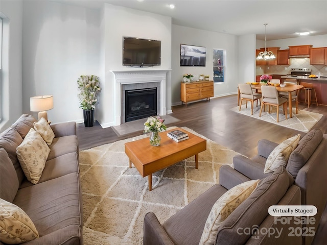 living area with a notable chandelier, baseboards, wood finished floors, and a tile fireplace