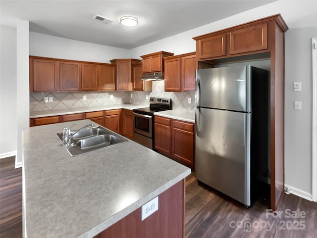 kitchen with stainless steel appliances, backsplash, a sink, and under cabinet range hood