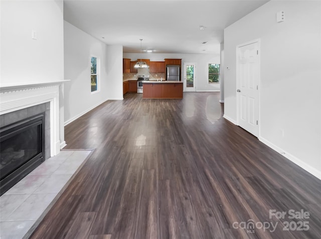 unfurnished living room featuring dark wood-style floors, baseboards, and a tiled fireplace