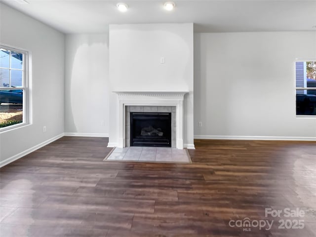 unfurnished living room with a fireplace, baseboards, and wood finished floors