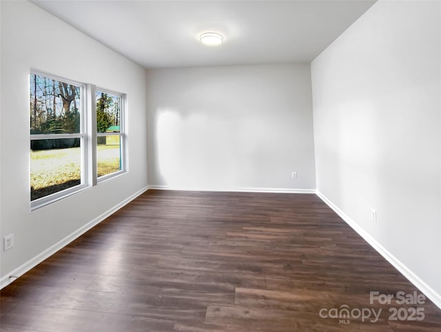 empty room featuring baseboards and dark wood finished floors