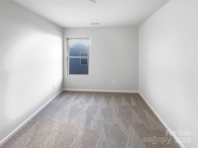 spare room featuring carpet floors, visible vents, and baseboards