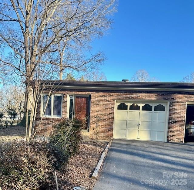 single story home featuring an attached garage, driveway, and brick siding