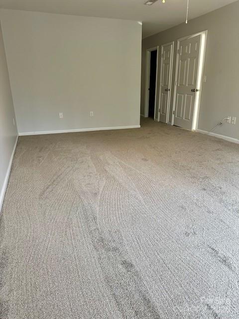 unfurnished room featuring carpet floors and baseboards