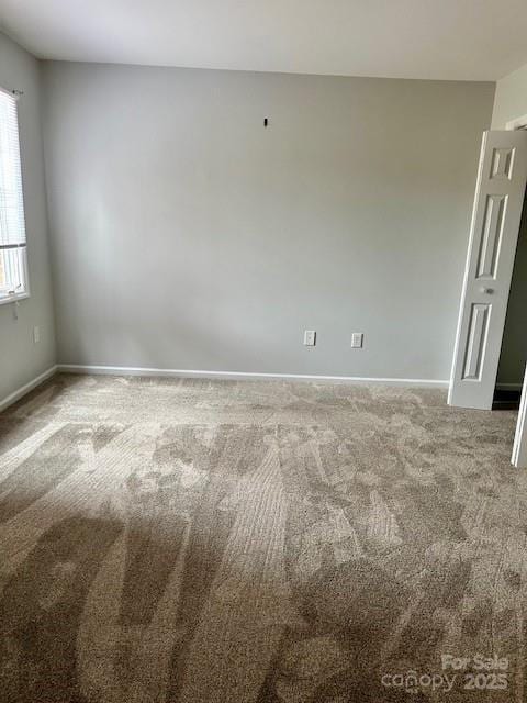 carpeted spare room featuring baseboards