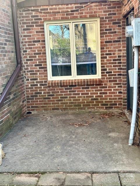 details featuring electric meter and brick siding