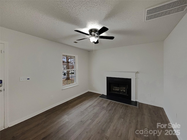 unfurnished living room with a ceiling fan, a fireplace, visible vents, and wood finished floors