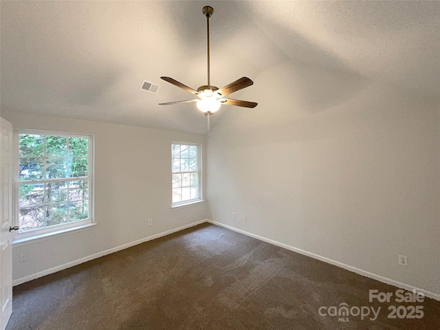 spare room featuring visible vents, baseboards, lofted ceiling, ceiling fan, and dark colored carpet